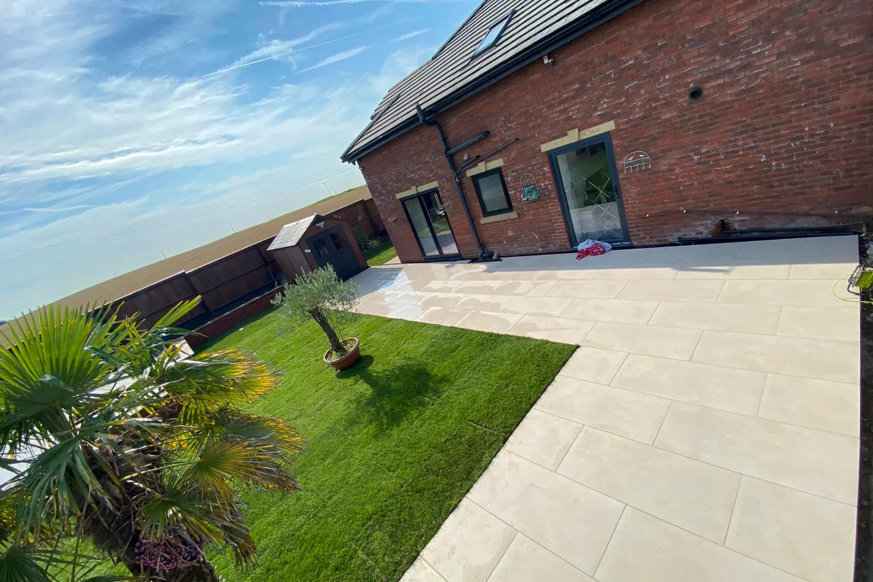 Country garden with pale porcelain terrace, pathways and lawn