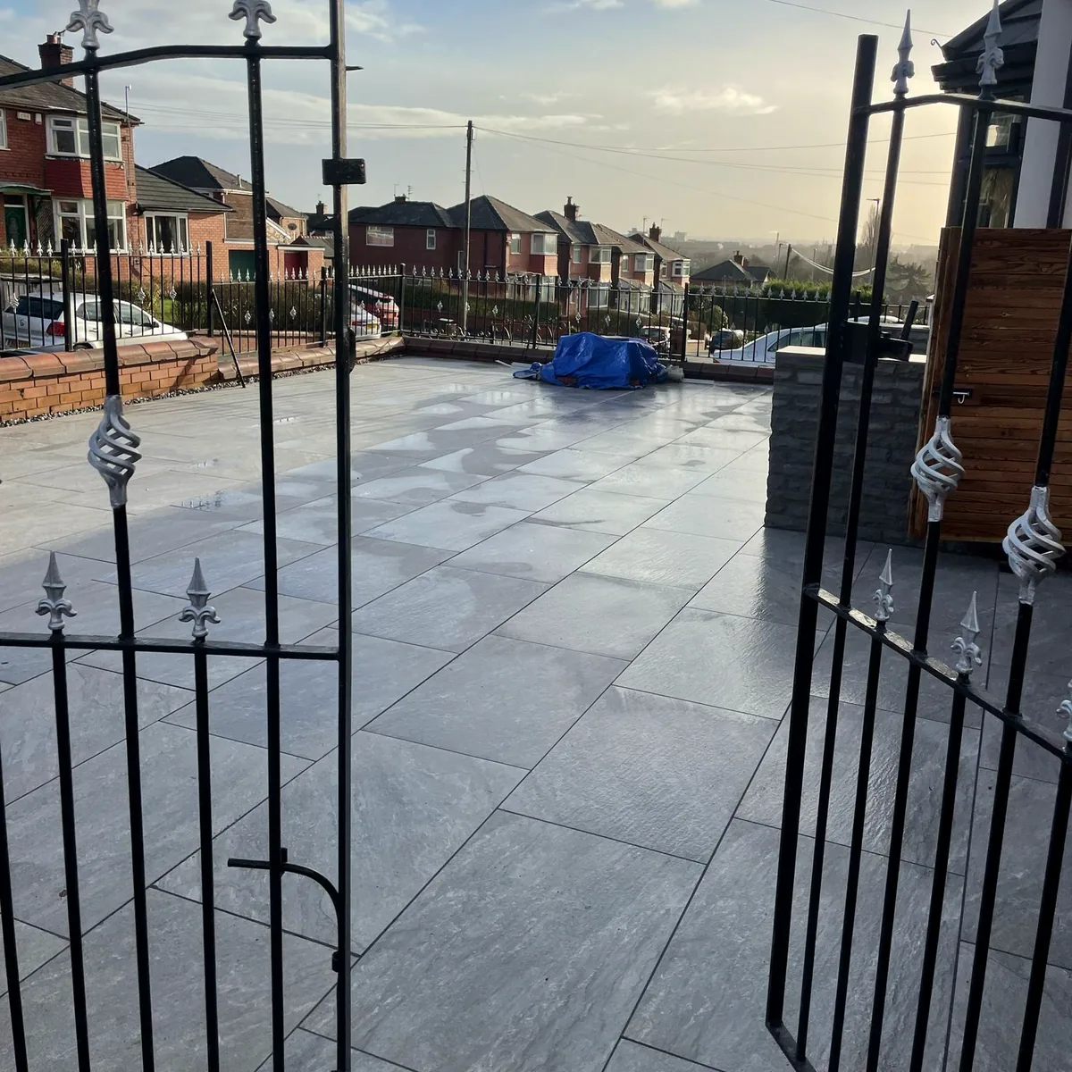 Grey porcelain driveway seen through open wrought-iron gates