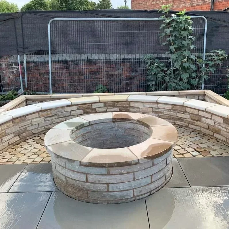 Circular stone fire pit inside a curved sandstone seating wall