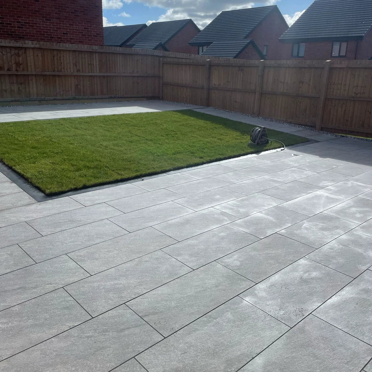 Large grey porcelain patio surrounding a newly laid lawn