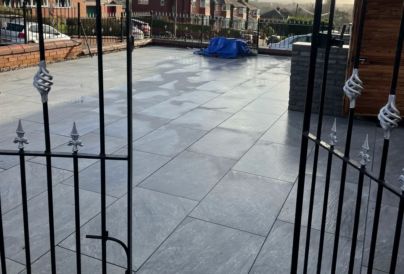 Grey porcelain driveway behind wrought-iron gates