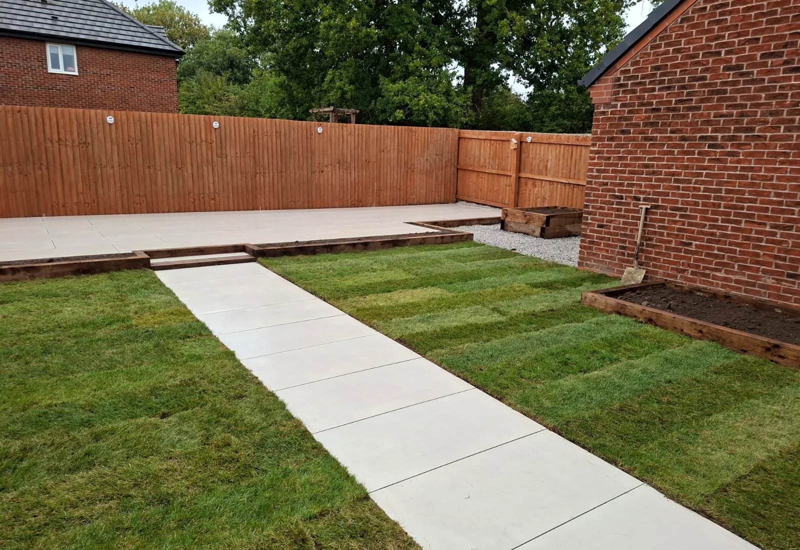 New lawn, porcelain path and timber-edged beds in a freshly landscaped back garden