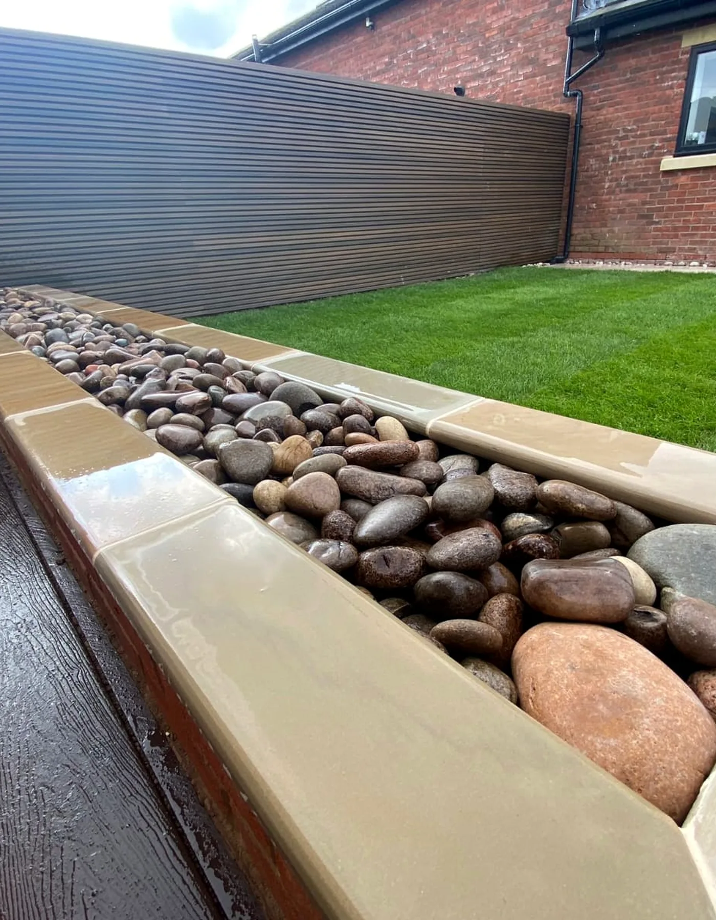 Close detail of sandstone coping and decorative river stones beside a finished lawn